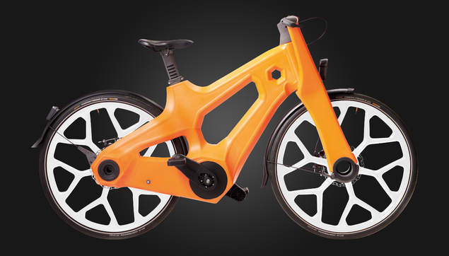Ein Fahrrad mit richtig dickem, orangefarbenem Rahmen, weißen Felgen mit dicken, weißen, sich baumartig verästelnden Felgen und armdicken Achsen — die vordere Achse ist sogar hohl und man kann durchschauen.

Der Antrieb ist im Rahmen gekapselt und die untere Streben des Hinterbaus ist so dick, dass sie den kompletten Zahnriemen umgreift.