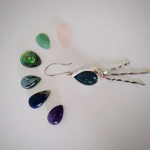 a dangle drop earring with blue teardrop shape gemstone (Labradorite). it has around it several teardrop shaped gemstones with various colors