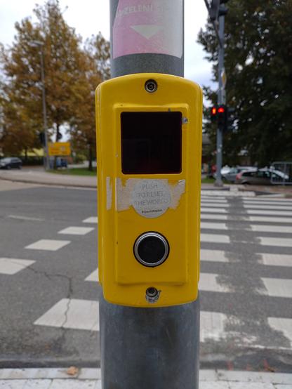 A pedestrian call button with the remnants of a 'push to reset the world' sticker.

Shot with Sony Xperia 10 III.
