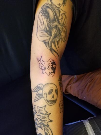 First flash tattoo is a goat head with an upside down star on its forehead, a flame between its horns, and wearing a spiked collar. Goat is facing down, placed on the side of an elbow.
