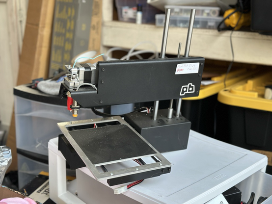 A Printrbot Simple Metal printer sitting on a set of plastic drawers in a garage.