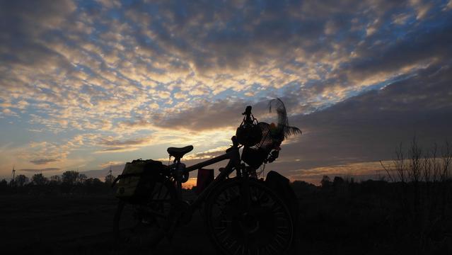 Schattenriss eines Fahrrades vor einem blauen Himmel mit Wolken