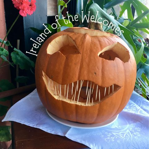 Ausgehöhlter grinsender Kürbis mit großen Augen und Zahnstochern als Zähne. Steht auf einem weißen Leinendeckchen mit irischem Muster (Kleeblatt und anderes).
Hollowed-out grinning pumpkin with big eyes and toothpicks for teeth. Stands on a white linen tablecloth with an Irish motif (shamrock and others).