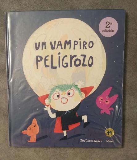 Portada de Un vampiro peligrozo.
Es de noche. Vemos a un pequeño vampiro vestido de negro, con camiseta y pantalones cortos, capa roja y pelo verde, que hace un gesto raro para intentar asustar.
A su izquierda un perro naranja y a su derecha un murciélago morado.
Detrás una gran luna llena que contiene el título.