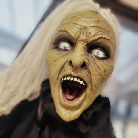 Gruselige Halloween-Puppe schaut direkt in die Kamera und reißt den Mund auf.