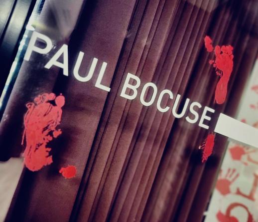 Die Türbeschriftung "Paul Bocuse" ist von zwei blutigen Fußabdrücken umgeben.