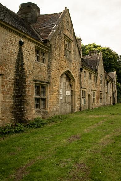 Old buildings with wooden gate in a grass field.