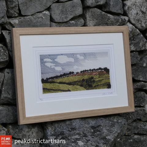 Framed print taken from a stitched artwork depicting rolling green hills with 25 trees on the horizon