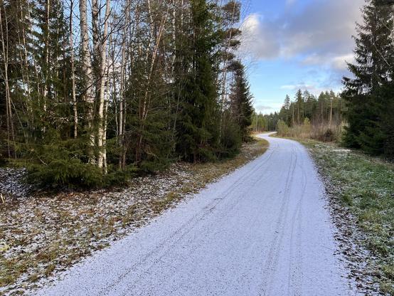 Kuntoradan mutka lähellä Heikinharjua. Ohut lumikerros tiellä. Taivaalla muutamia isoja pumpulipilviä.