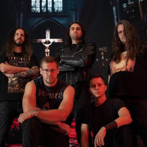 Die Band vor einem Kirchenhintergrund. Hinten ein großes Kreuz. Drei Bandmitglieder stehen, zwei kniend davor. Alle gucken grimmig.