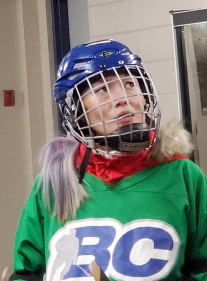 Me in green BC Games hockey jersey & blue hockey helmet, looking up to the right with a puzzled expression