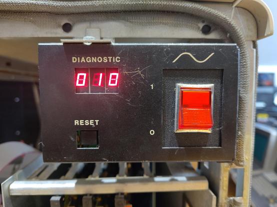 An oblong black panel a bit bigger than a deck of cards. There is a big red power switch at right. At bottom left is a black button with the word “RESET” printed above it; at top left, beneath the word “DIAGNOSTIC”, is a three-digit 7-segment LED display that reads 010.
