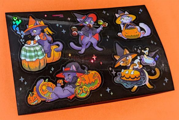 A photo of a sticker sheet featuring Halloween-y witch kitties eating festive treats