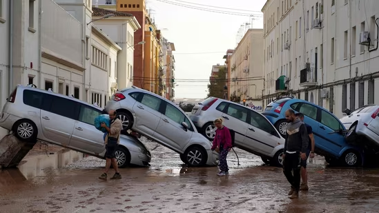 Residents walk past piled up cars following deadly floods in Valencia's De La Torre neighbourhood, south of Valencia, eastern Spain, on October 30, 2024.(AFP)