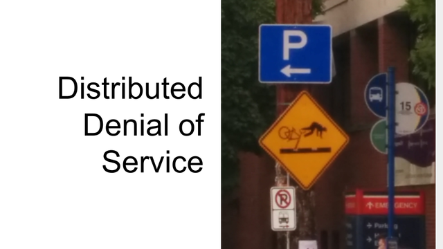 A slide from my BSidesPDX 2024 talk which reads "Distributed Denial of Service" and has photo I took of some street signs near the train tracks. The relevant one is a large yellow caution sign that shows a person with a bike getting a wheel stuck in the train tracks and the rider is being launched off the bike over the tracks.