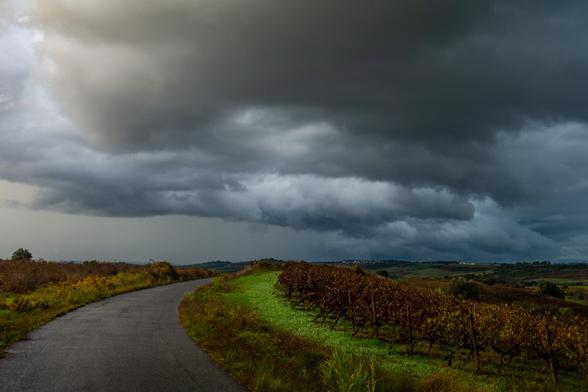 country road curving away to the right towards a sky full of storm clouds in Portugal