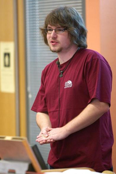 Já na LinuxAltu 2010.

Rudé (vínové?) tričko s logem LinuxAlt 2010. Mikrofon na límci. Ruce spjaté, výraz soustředěný. Vlasy kratší, fousy skoro žádné.

Z https://archiv.openalt.org/linuxalt-cz/2010/fotogalerie.html