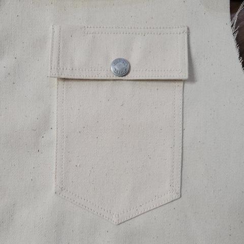 A chest pocket on a white sateen jacket under construction