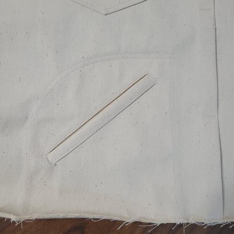 A front pocket on a white sateen jacket under construction