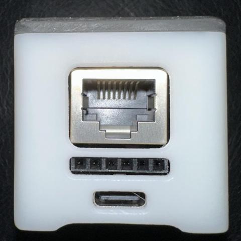 A white square with an embedded Ethernet port above a custom 8-pin port and a USB-C port.