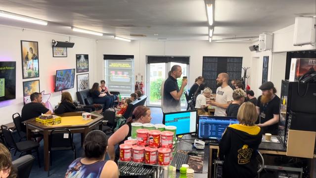 view of a room supporting lots of gaming activities like boardgames and videogames. its filled with people.