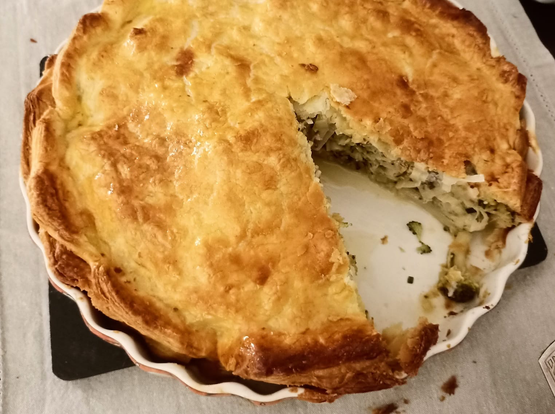 Der fertige knusprig-braune Brokkoli-Kuchen in der Tarte-Form, ein Stück wurde schon herausgeschnitten.