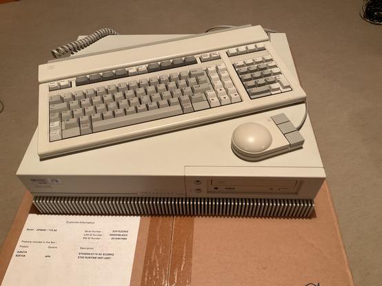 HP 9000 715/50 workstation with HP-HIL keyboard and mouse sitting on its shipping box.
