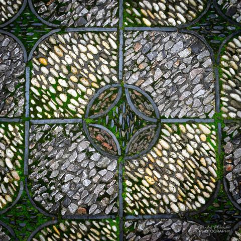 Stones of different colors and sizes with moss growing between them for a pattern on the paths of a Chinese garden.