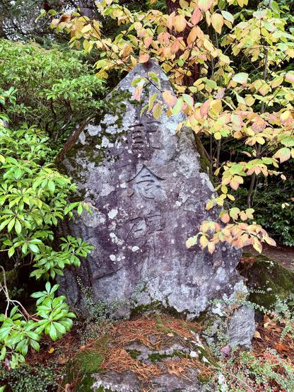 Memorial Stone with Japanese text inscribed on it surrounded by trees