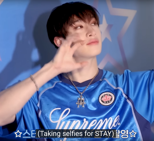 Bang Chan wearing a pendant necklace with 3 overlapping flared crosses, and also his regular round flower cross bracelet