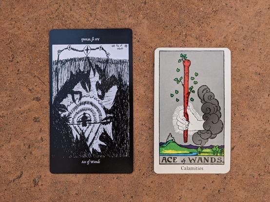 The Ace of Wands from the Elsewhere Tarot, showing a rough, sketchy drawing of a  figure in a robe at a table from which waves of power are spreading outward, driving back large, shadowy, menacing creatures with sharp claws and sharp beaks, alongside the Ace of Wands from a janky, bootleg RWS deck, showing a glowing hand holding a living wand above a rolling landscape of a castle, hills, and a river.