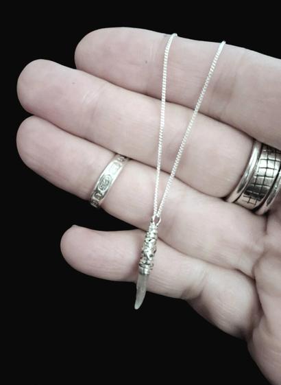 hand holding a selenite and silver pendant,  on black background