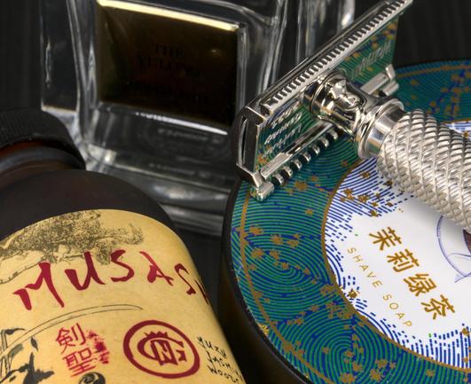 A shiny polished WR2 on a tub of NO 茉莉綠茶 next to a bottle of GN Musahi splash and a bottle of GA Thé Yulong frag