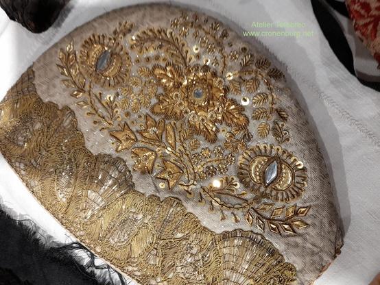 A white bonnet with precious floral embroidery in gold, ornated with sequins and rhinestones. These threads were pure gilded metal.