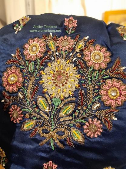 A precious dark blue satin bonnet with a rich embroidery of gold thread and glass rocailles. The circle of flowers around one big flower and some grain ears symbolised the Tree Of Life, a traditional pattern in Alsatian popular art.