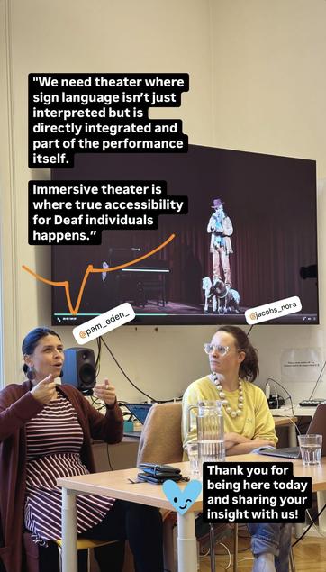 This image is from the same presentation, with the two individuals, “@pam_eden_” and “@jacobs_nora,” still seated at the table. The screen now displays a theater performance image, showing a person on stage under a spotlight, dressed in costume, accompanied by a few small animals.

Overlay text in English reads:

"We need theater where sign language isn’t just interpreted but is directly integrated and part of the performance itself.
Immersive theater is where true accessibility for Deaf individuals happens."
The presenter, “@pam_eden_,” is gesturing with both hands as if demonstrating something related to the topic. The person tagged as “@jacobs_nora” listens intently. At the bottom right, there’s a small blue heart sticker with a smiley face and a message that reads:

"Thank you for being here today and sharing your insight with us!"