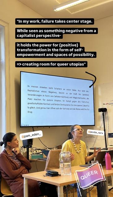 This image captures a presentation in a classroom setting. Two individuals, tagged as “@pam_eden_” and “@jacobs_nora,” are seated at a table in front of a screen displaying text. The screen text is in German, and above it, in large overlay text, there’s an English translation.

The English translation reads:

"In my work, failure takes center stage.
While seen as something negative from a capitalist perspective – it holds the power for (positive) transformation in the form of self-empowerment and spaces of possibility.
=> creating room for queer utopias."
The German text on the screen reads:

"In meinen Arbeiten steht Scheitern an erster Stelle. Aus Sicht des Kapitalismus etwas Negatives, besitzt es eine Kraft für (positive) Veränderungen in Form von Selbstermächtigung und Möglichkeitsorten, die Platz machen für queere Utopien; Im Kampf gegen das Patriarchat, gesellschaftliche Normen und binäre Denksysteme für eine queere Zukunft à la glitch. Und genau hier öffnet sich der Vorhang und die Bühne wird frei für Drag."
One of the presenters, identified as “@pam_eden_,” is sitting thoughtfully, hand near her chin, wearing a striped dress and a maroon cardigan. The other, “@jacobs_nora,” dressed in a yellow top and large, round white bead necklace, is mid-sentence, gesturing expressively. In the corner, there’s a rainbow-colored graphic with the word "QUEER."