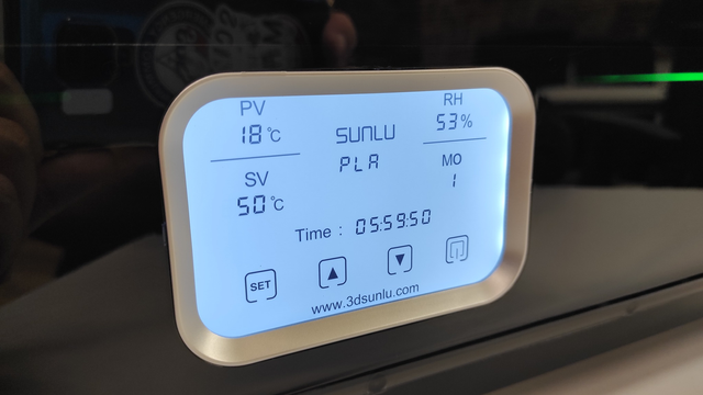 The digital screen on the front of the SUNLU filament dryer displays real-time settings. The screen shows "PV" (Process Value) at 18°C, "SV" (Set Value) at 50°C, and "RH" (Relative Humidity) at 53%, along with the filament type "PLA" and a mode setting "MO 1." A countdown timer displays a remaining drying time of 5 hours, 59 minutes, and 50 seconds. Various icons at the bottom of the screen represent control options, such as setting adjustments, making the display user-friendly for precise filament drying.
