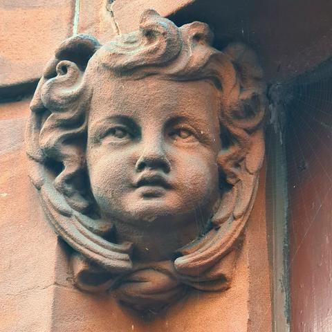 A skillfully carved putti on an Edwardian Baroque red sandstone Glasgow building.