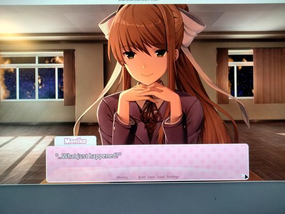 The putative dating sim character Monika is look directly at the viewer, her chin resting on the backs of her fingers. She has a slight, knowingsmile, brown eyes, and a large, light lavender hair bow. A Brunette, her hair is very long. She is sitting in a room; the view through the windows is of nebulae; the scene, cosmic. She is saying "What just happened?"