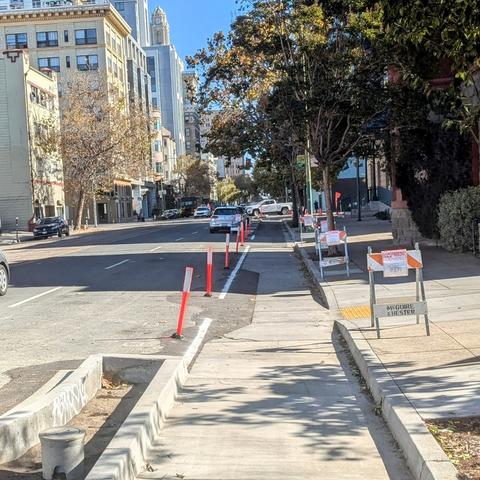 Photo of bike lane under construction with temporary orange plastic posts marking the bike lane so cars won't park in it