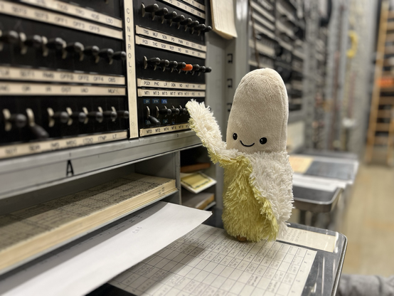 A small stuffed banana smiling and operating a lever-key at a test frame.