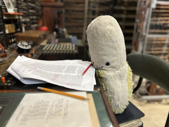 A stuffed banana smiling and holding a pencil.