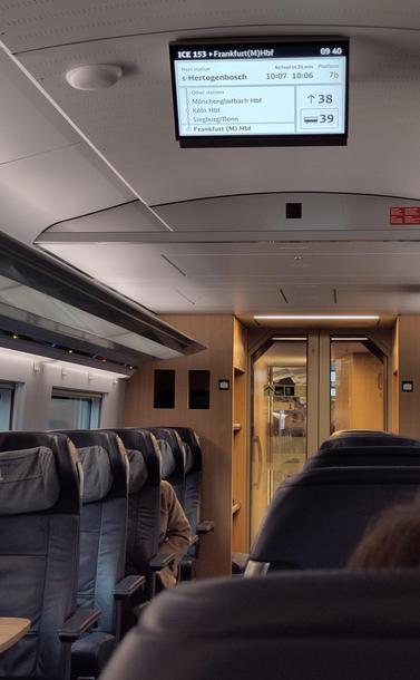 A photo from inside of an ICE 3 neo in first class. The display shows ICE153 to Frankfurt Hbf