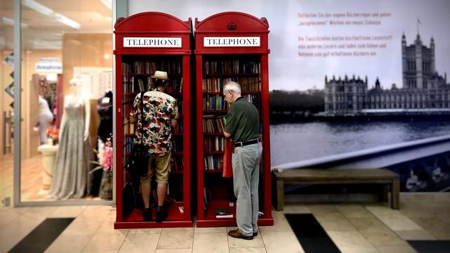 Two men in a public-lending library phone-booth in Harburg near Hamburg Germany (taken August 2019)