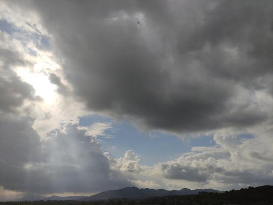 cielo con nubes oscuras, en una zona hay un claro. Los rayos de sol atraviesan por un lado donde las nubes son menos espesas dando un aspecto divino y celestial a la imagen