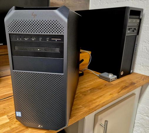 A nice, grey and black HP Z4 G4 workstation computer on a wooden desk, with an older Z440 workstation in the background. It's got a row of ports under the HP logo and a slim DVD-drive in the 5.25 inch bay.