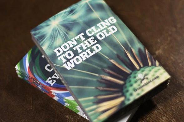 A stack of copies of the pamphlet, To Change Everything. The top one is turned over so that you can see that the back reads "Don't cling to the old world."