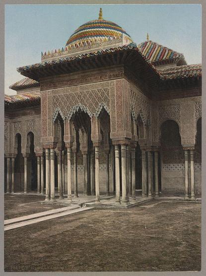 The image depicts the architectural beauty of a patio in the Alhambra palace complex located in Granada, Spain. This particular scene showcases an ornate pavilion with intricate lattice work and detailed tile mosaics on its walls and ceiling. The structure is supported by multiple columns featuring classical design elements like fluted shafts and decorative capitals.

In the center of the patio stands a fountain or water feature that adds to the serene ambiance, while a pathway leads through the courtyard, creating an inviting space for visitors to stroll. Above, the dome exhibits vibrant colors with patterns in shades of blue, yellow, red, and green on its outer surface, reflecting Islamic architectural influences.

The overall setting suggests a historical significance, as this palace complex was built during different eras between the 13th and late-15th centuries under various Muslim empires. The image captures the essence of Arabic artistry through its harmonious blend of geometric patterns, arabesques, and vibrant colors that create an atmosphere steeped in cultural richness.

As a piece from Photoglob Company's collection, circa between 1890 and 1906, this photograph is part of their series documenting various landmarks around the world. It serves as an essential visual record for those who might not have had access to visit these historical sites firsthand during that period.