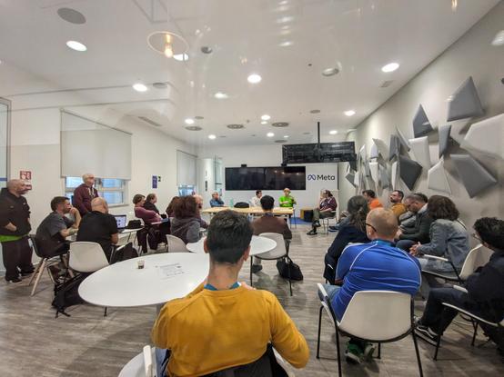 A crowded room during the Rome Core Days 2024, with several people sitting and discussing